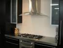 Galley kitchen featuring stainless top and curved glass rangehood